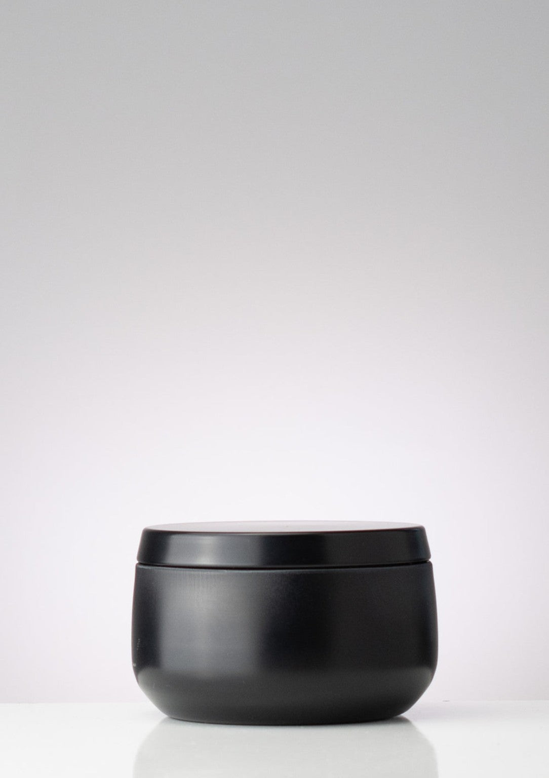 Rounded matte-black candle tin with matching lid