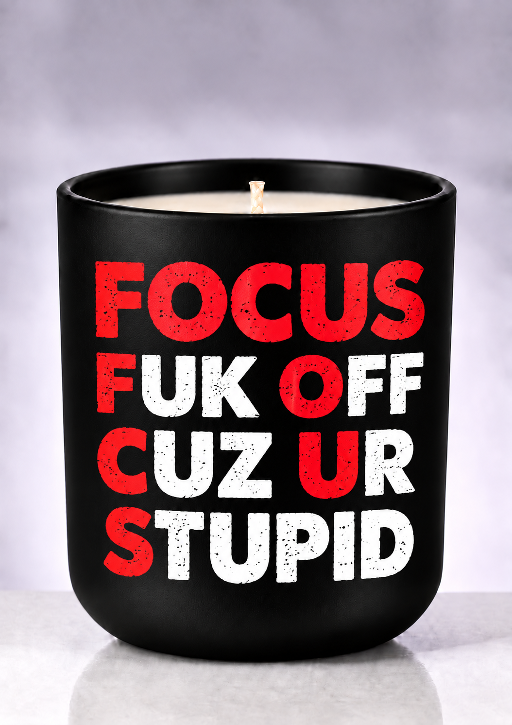 FOCUS candle with red initials and white FUK OFF CUZ UR STUPID lettering on a matte-black jar