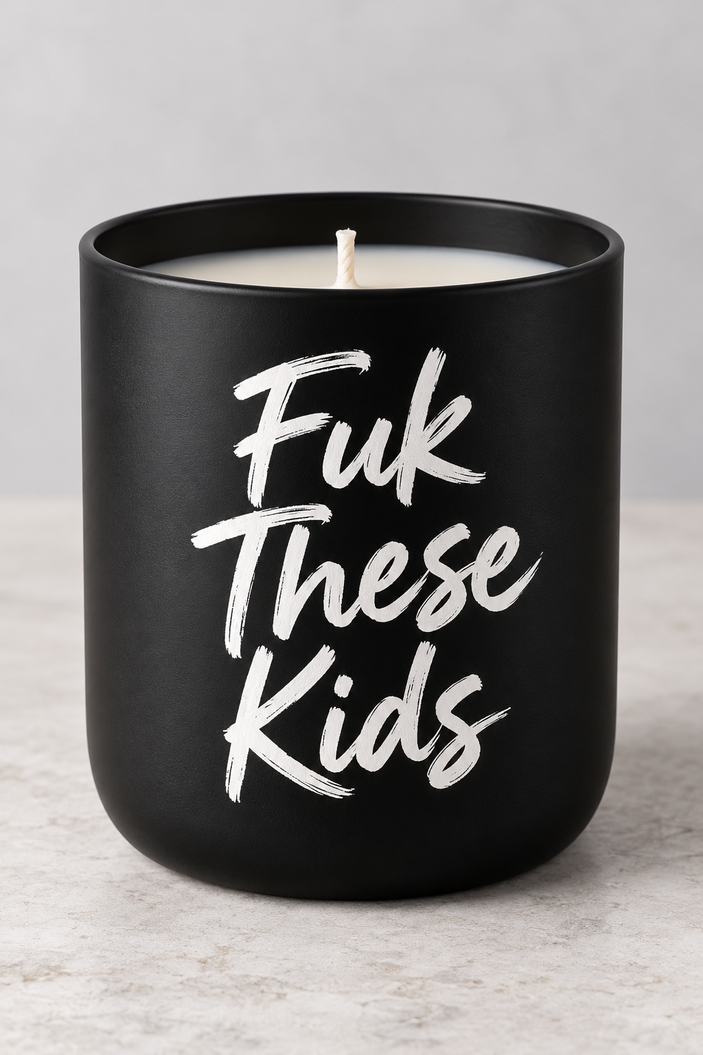 Fuk These Kids soy candle with white brush-script on a matte-black jar