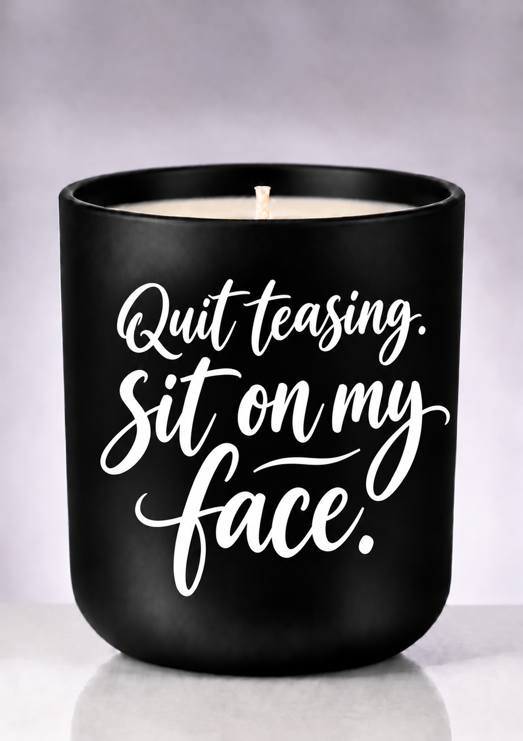 Quit teasing statement candle with white script on a matte-black jar